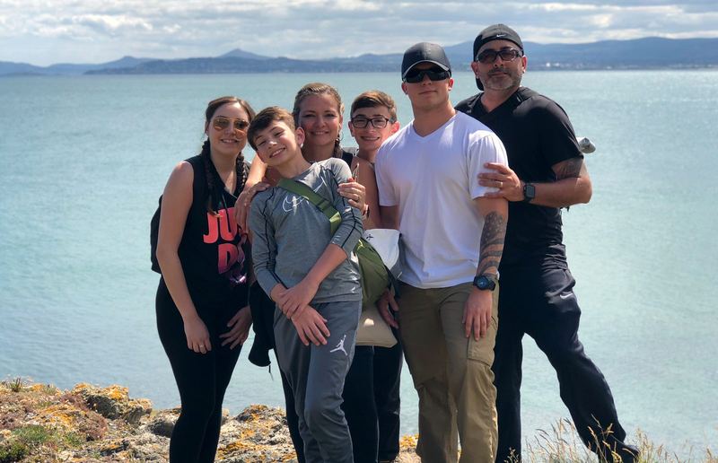 Artie and family on a green coastal cliff over blue water