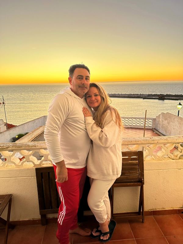 Artie and April on a terrace over the ocean at golden hour