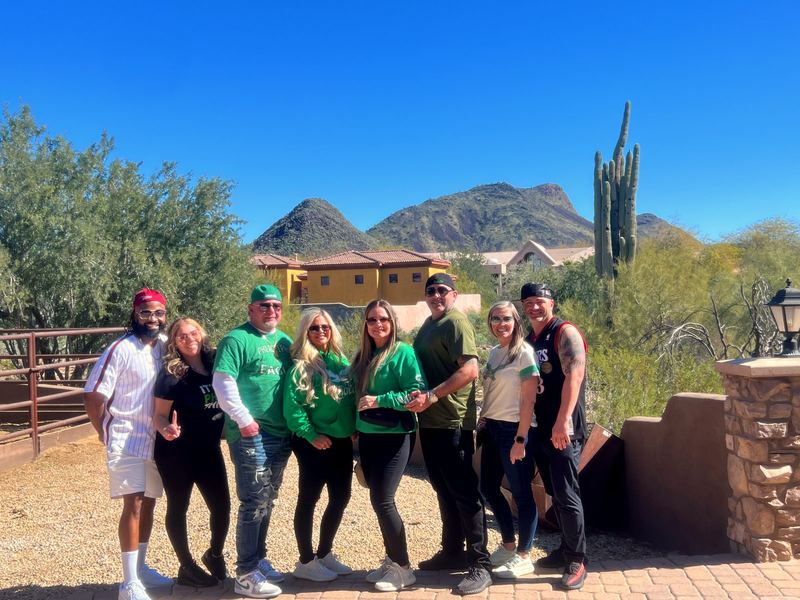 Artie, April, and friends in the desert with cactus and mountains behind